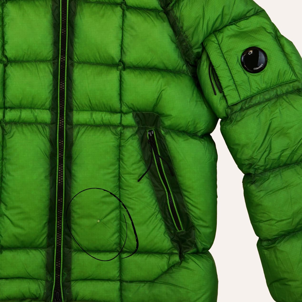 Example 10: Green DD Shell jacket with a hole near the front zip.